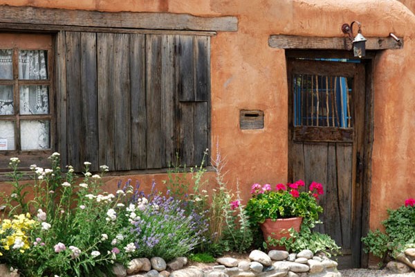 Adobe House with Dark Wooden Windows and Door and Colorful Spring Flowers